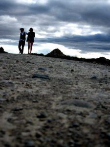 Dos figuras caminando sobre un terreno árido bajo un cielo nublado, evocando la pregunta: ¿Qué dice la Biblia sobre el abandono de hijos por parte de los padres?