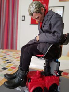 A seated male action figure in a gray coat and boots looking down, illustrating What the Bible says about being a bad husband: A comprehensive guide.