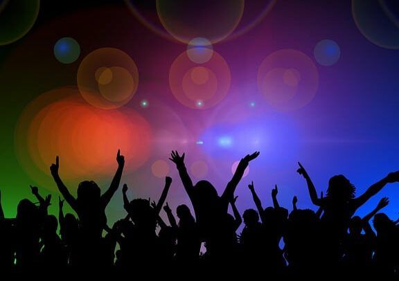 ¿Es pecado bailar? Lo que dice la Biblia sobre la danza en una escena de siluetas bailando bajo luces de colores.