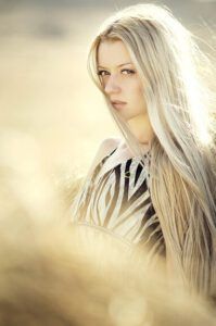 Mujer de cabello rubio largo en un campo iluminado por el sol, mirada serena — ¿Qué enseña la Biblia sobre la belleza femenina?