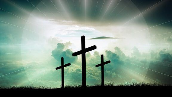 Tres cruces en silueta frente a un cielo dramático y rayos de luz que invitan a la reflexión: ¿Cómo saber si la Biblia ha sido alterada a lo largo del tiempo?
