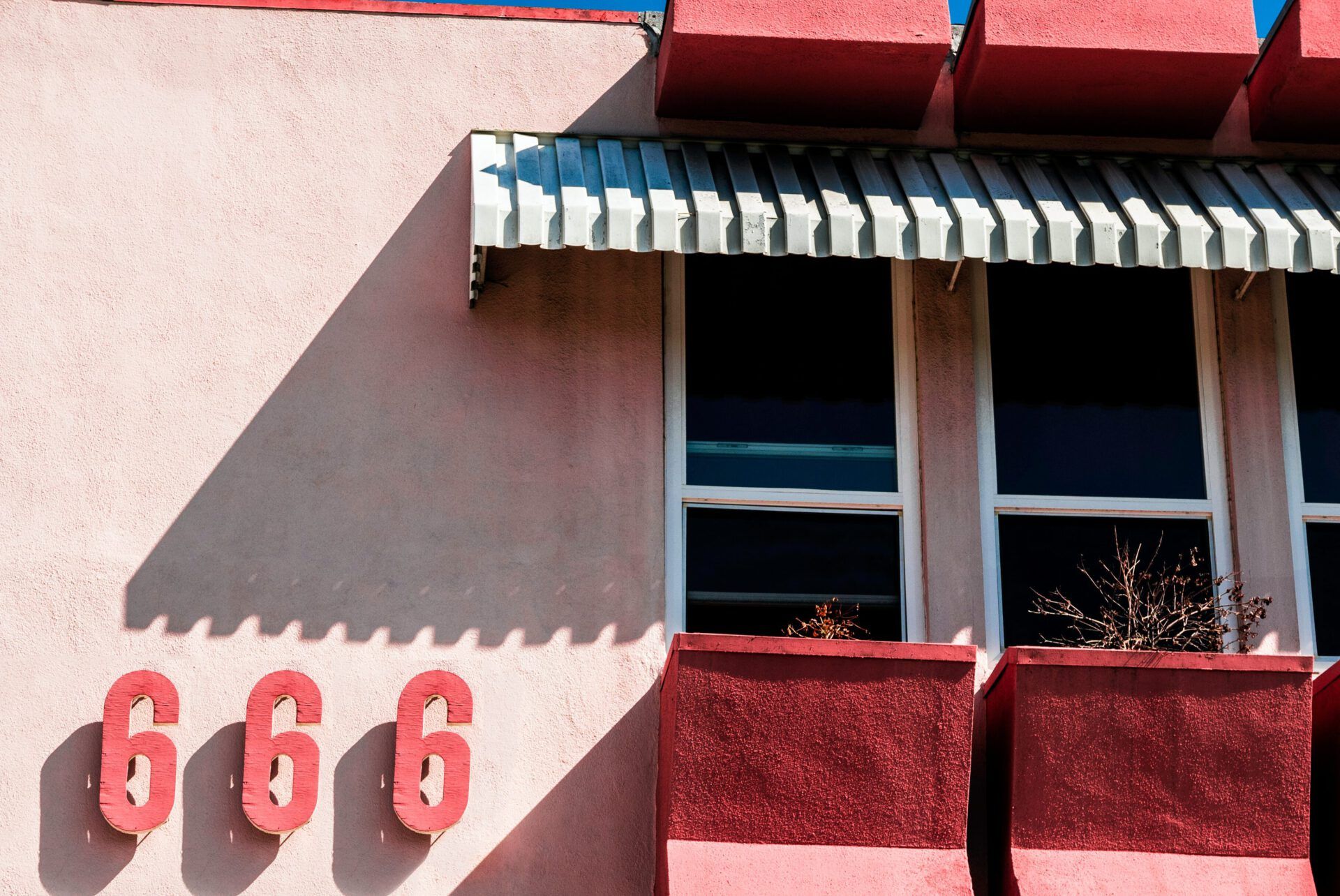 Fachada rosada con tres números 666 en rojo y ventanas: ¿Qué dice la Biblia sobre el número 666? Descubre la verdad aquí