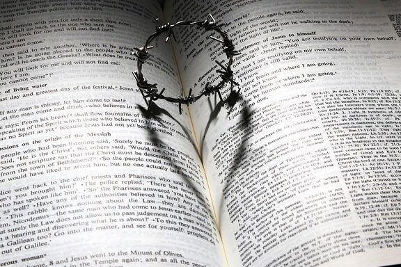 Biblia abierta con una corona de espinas que proyecta un corazón, evocando reflexión y la pregunta ¿Qué significa 'de tiempo en tiempo' en la Biblia? Descubre su verdadero significado aquí