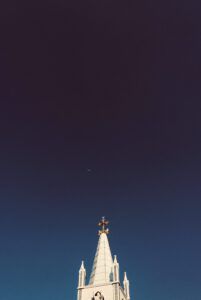 Iglesia blanca con aguja y cruz bajo la luna, evocando Lo que la Biblia revela sobre la edad de 9 años.