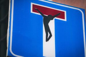 Señal de calle sin salida con una silueta de crucificado en el extremo superior que provoca la pregunta ¿Qué dice la Biblia sobre la amistad?