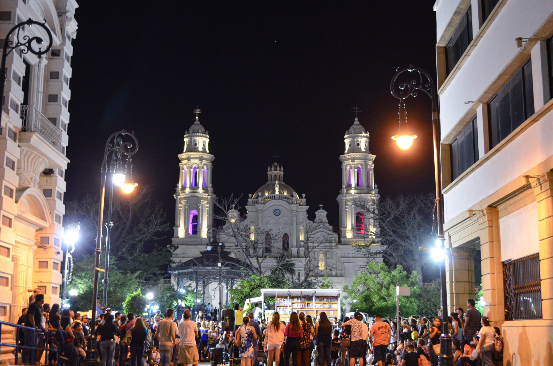 Multitud reunida en una plaza nocturna frente a una catedral iluminada mientras surge la pregunta ¿Es pecado convivir sin casarse según la Biblia?