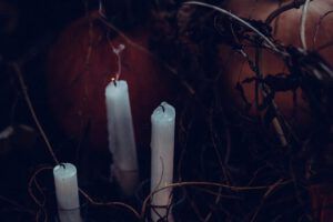 Velas blancas entre ramas y calabazas en penumbra evocan misterio: Los 7 demonios según la Biblia: ¿Qué revela sobre el mal?