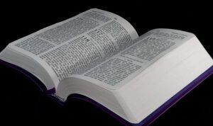 Biblia abierta sobre fondo oscuro que invita a la reflexión: ¿Qué revela la Biblia sobre la naturaleza de Dios?