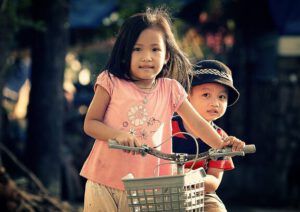Dos niños sonrientes en bicicleta al aire libre: ¿Qué enseña la Biblia sobre la educación de los hijos? Descubre sus consejos aquí