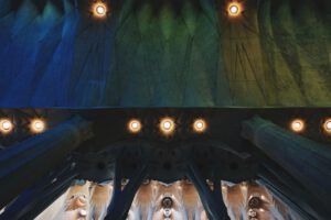 Vista interior de bóvedas y columnas con luces cálidas y tonos verdes y azules, que invita a la reflexión; ¿Qué dice la Biblia sobre alejarse de la familia? Descubre la verdad aquí