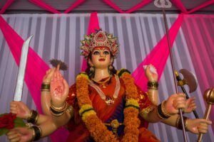 Colorful multi-armed Hindu goddess statue with marigold garlands and ritual weapons, a striking tableau prompting reflection on Why the Bible says we can't see God and what it means for our faith