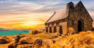 Iglesia de piedra junto a un lago al atardecer que inspira reflexión: Lo que la Biblia revela sobre la verdadera naturaleza de la iglesia