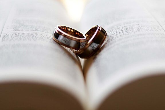 Anillos de boda sobre una Biblia abierta simbolizando Matrimonio en el Nuevo Testamento: Lo que la Biblia Revela.
