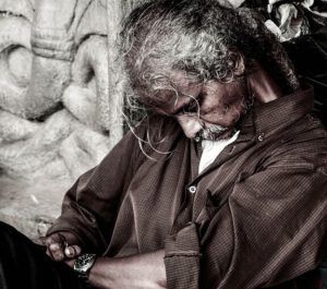 Hombre mayor sentado dormido con cabello canoso, barba incipiente y camisa arrugada, reloj en la muñeca; ¿Qué dice la Biblia sobre la mujer mayor que el hombre? Descubre la verdad bíblica aquí