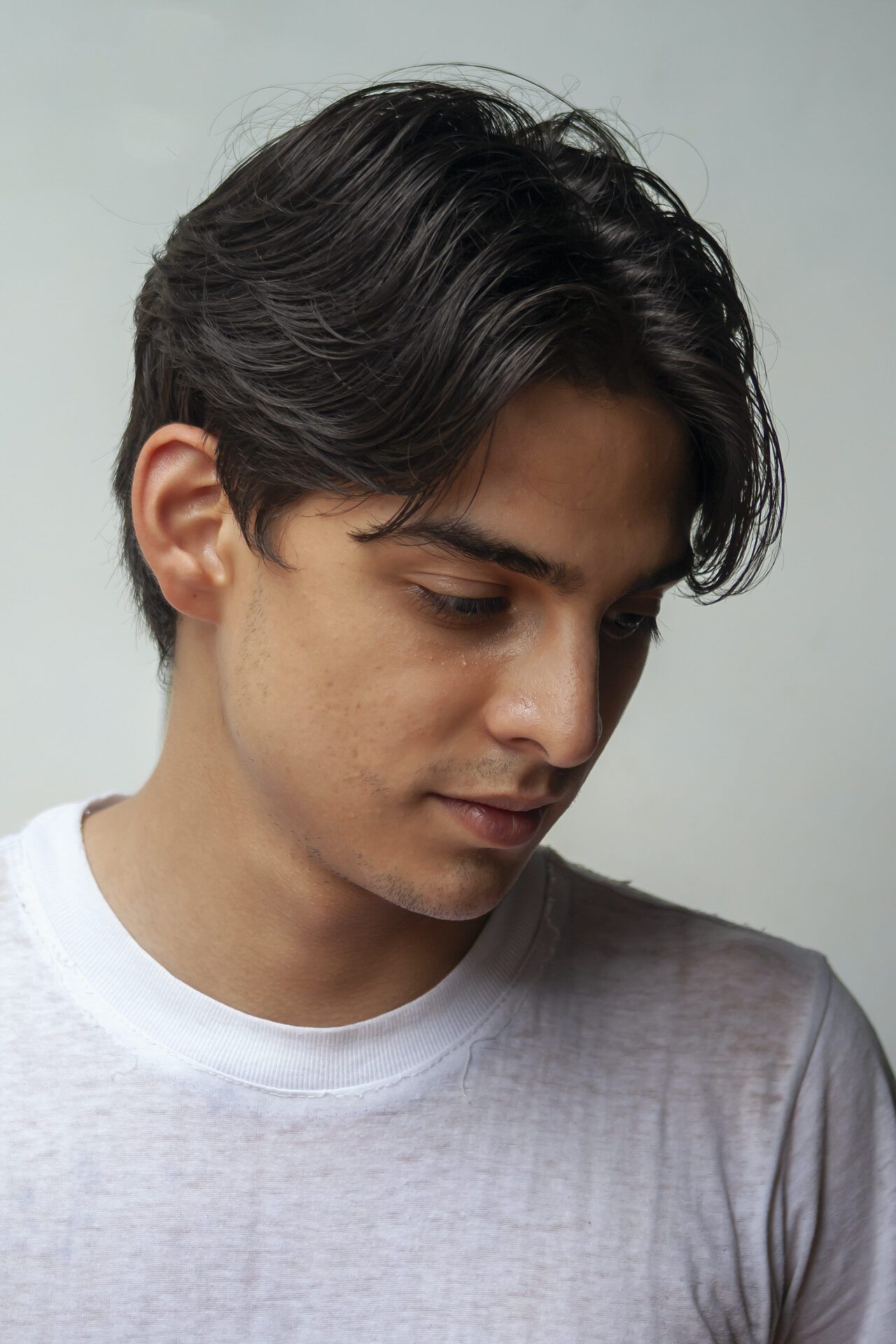 Joven pensativo con mirada baja, evocando la pregunta ¿Qué dice la Biblia sobre la muerte de un niño?