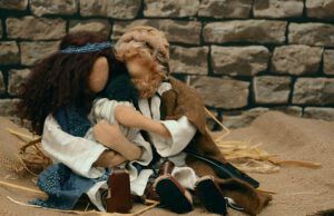 Muñecos de tela abrazando a un bebé en un entorno rústico, ¿Qué enseña la Biblia sobre la crianza de los niños?