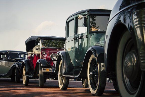 Fila de automóviles clásicos y vintage estacionados en una calle con énfasis en llantas y parrillas; ¿Qué sucede después del rapto según la Biblia? Descubre la verdad aquí