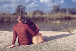 Pareja abrazada junto a un río contemplando la orilla, 5 consejos bíblicos para solucionar conflictos de pareja