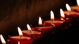 Filas de velas votivas rojas encendidas en un fondo oscuro que crean una atmósfera cálida y contemplativa — ¿Qué dice la Biblia sobre encender velas? Descubre la verdad aquí