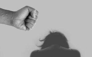 Mano cerrada amenazante sobre una figura encorvada, ¿Es justificable la violencia de género según la Biblia?